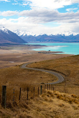 Naklejka premium NZ fence runs down to road in front of lake