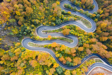 Aerial view of road in beautiful autumn forest at sunset.