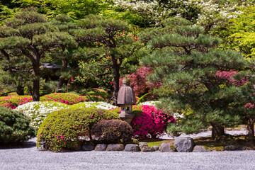 A traditional Japanese style garden with colorful l foliage and blooms, and tall stone lantern