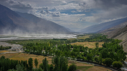 Panorama view of Wakhan Corridor in Tajikistan Pamir mountains with Hindu Kush range in Afghanistan and sandstorm on Panj river