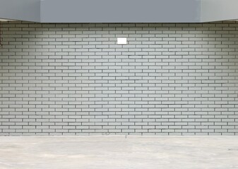 Light gray brick wall with a gray panel above and a concrete pavement in front. Background for copy...