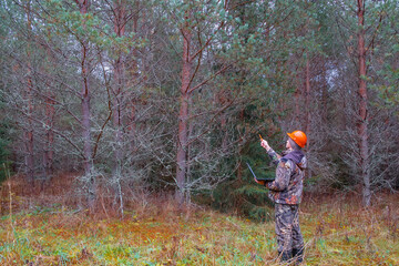 A forest engineer works in the forest with a computer. Forest worker performs forest inventory. Digital technologies in forestry.