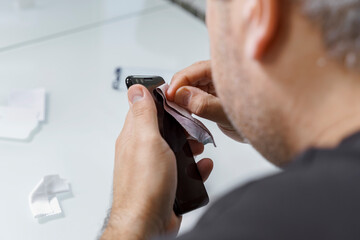 a man changes the protective glass on a smartphone