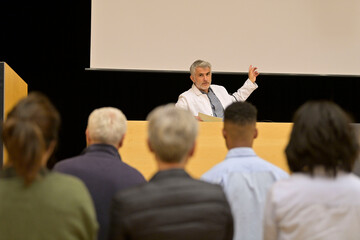 Doctor giving conference in convention center, audience in rear view