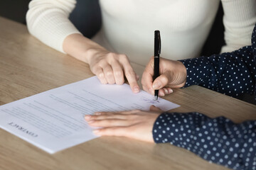 Close up Indian woman client signing contract, making deal with realtor broker, manager pointing...