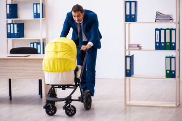 Young male employee looking after kid at workplace