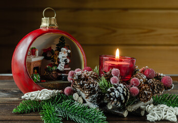 Candlestick with a burning candle, branches, spruce, artificial berries, Christmas toy close-up.