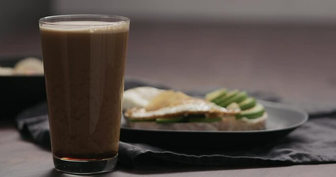 Slow motion stout beer in pint glass with food on background