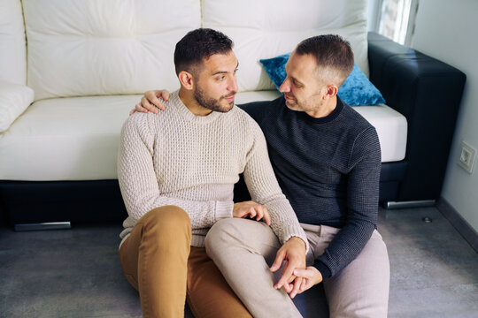 Gay couple sitting near the couch at home in a romantic moment