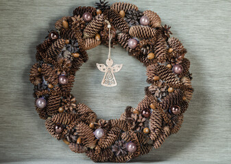 Christmas wreath in natural style with a figurine of an angel on a gray background close-up