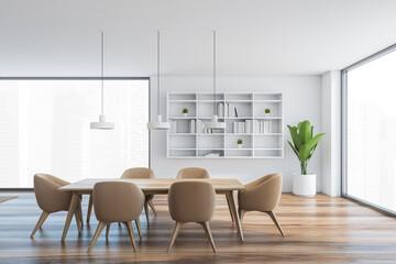 White wooden hall with brown chairs, wooden table, bookshelf and windows