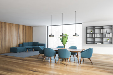 White wooden hall with blue chairs and sofa and wooden table and big window