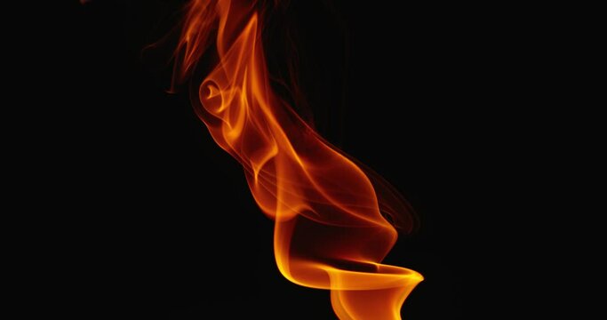 Slow movement of artsy clouds and swirls of orange smoke against a dark background. The movement of tongues of orange flame.