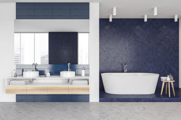 Blue and white bathroom with bathtub and sinks on grey floor