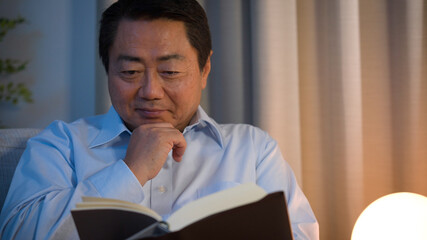 ソファーで本を読んでいる中年男性