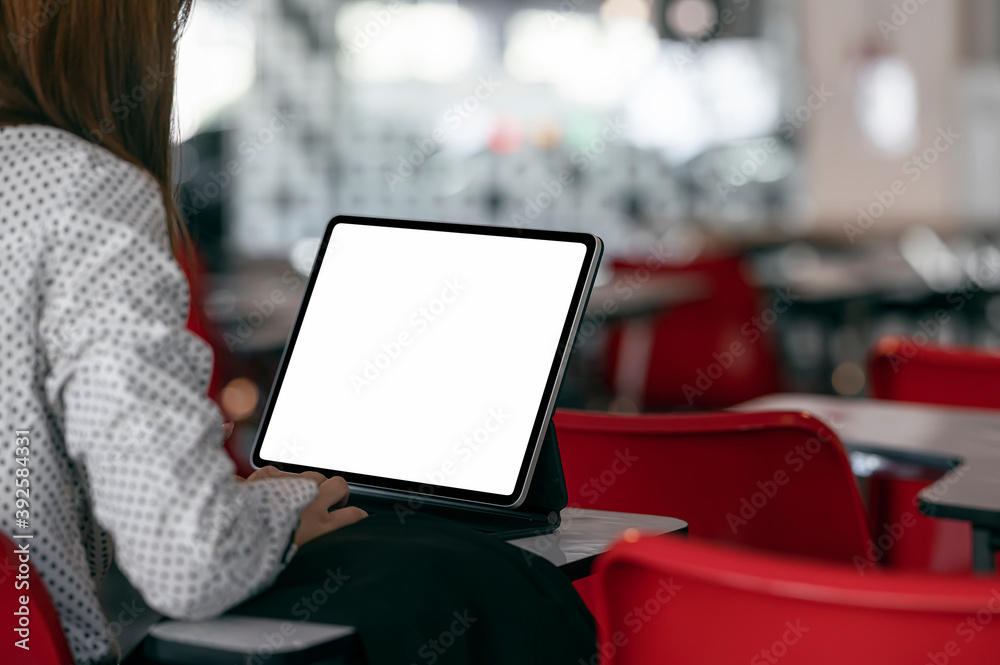 Fototapete Closeup image of young female university student using tablet while sitting in lecture room, blank screen for graphic design.