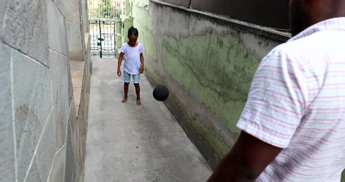 Father kicking ball to son, African dand and child playing soccer together