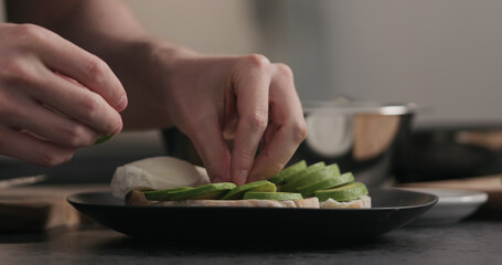 man makes sandwich with avocado and cream cheese