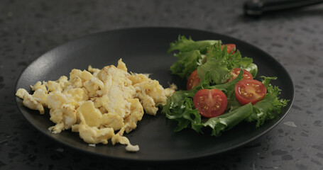 scrambled eggs on black plate with salad