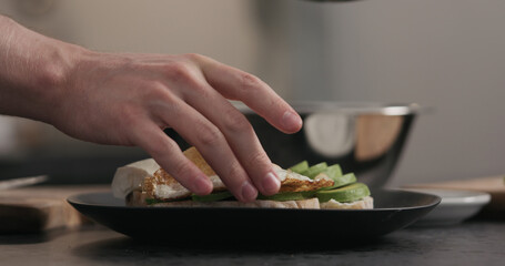 man makes sandwich with avocado and fried egg