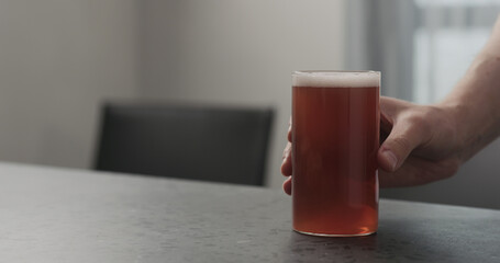 Slow motion man hand take orange soft drink in highball glass from concrete countertop with copy space
