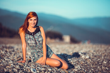 Beautiful young woman enjoing herself on pebble sunny beach