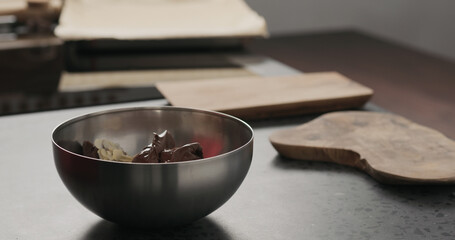 Slow motion making granola, add chocolate spread in steel bowl on concrete countertop