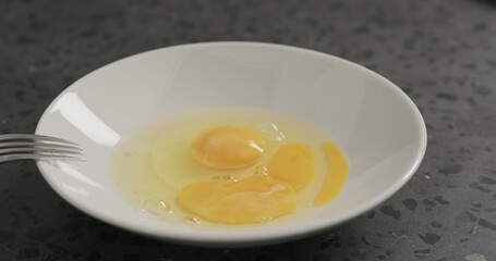 Slow motion egg fall into white bowl on concrete background
