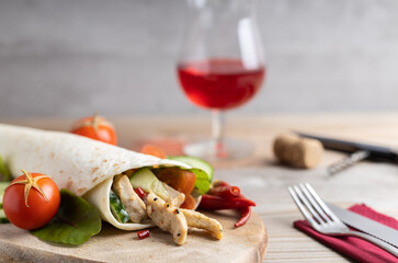 Tortilla wraps filled with grilled chicken and fresh vegetables. On a wooden table. Outdoors, fast food concepts