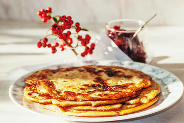 Fried pancake on plate, jam and red berries.