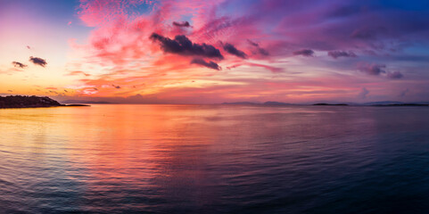 Fototapeta na wymiar A beautiful sunset over the calm sea with red, orange and pink clouds reflecting in the water