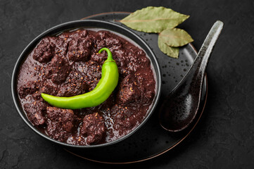 Dinuguan in black bowl on dark slate table top. Spicy filipino cuisine Pork Blood Stew dish with...