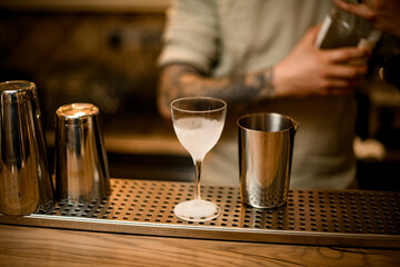 different glasses and jigger and measuring cup are stands on bar counter.