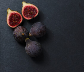 Still life of black figs. Three whole figs and one split fig. Dark Food