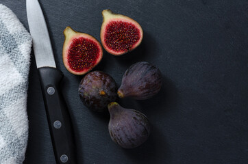 Still life of black figs. Three whole figs and one split fig with a knife. Dark Food