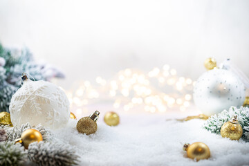 Christmas gold decorations on snow with fir tree branches and christmas lights. Winter Decoration...