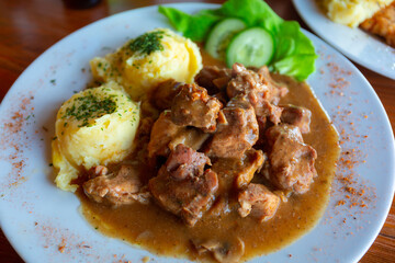 Pork goulash with potatoes and salad od the plate
