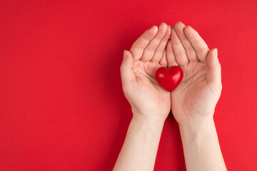 Donation concept. Top above overhead view photo of female hands holding red heart isolated on red background with copyspace