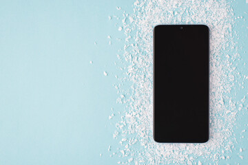 Top above overhead view layout photo of black smartphone on snow isolated on blue background with copyspace