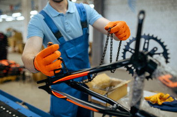 Bicycle factory, worker holds bike chain