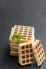 Stack of toasting waffles with chocolate on black stone background