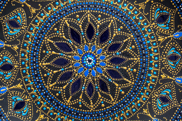 Decorative ceramic plate with black, blue and golden colors, painted plate on background , dot painting