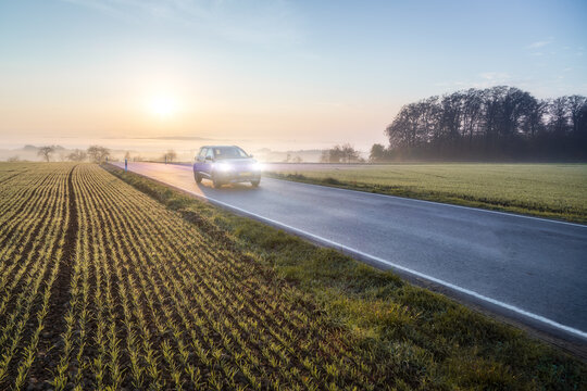 Car driving on Luxembourgish rural road during sunrise near field