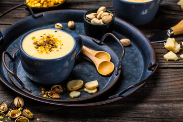 bowl of cream of corn soup with pistachios and croutons on top, vertical image, Vegan cuisine. Restaurant menu, dieting, cookbook recipe