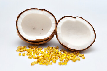 Health care - Nutritional supplement and Healthy food - Halved coconut with scattered gold gel capsule on the front. Isolated on white background