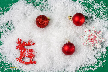 Christmas or New Year's composition. Christmas red balls and figurine of a deer in the snow on a...