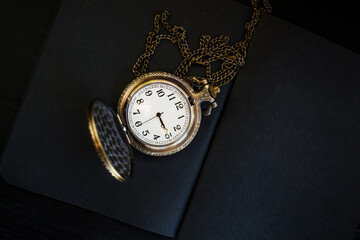 Pocket watch on black matte paper. Open notebook on a black wooden table. - 392594932