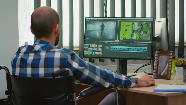 Disabled freelancer videographer editing postproduction a video project creating content sitting in wheelchair in modern company office. Creator blogger working from modern photo studio.