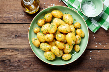 Fresh boiled new potatoes with fresh dill on wooden background.top view