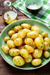Fresh boiled new potatoes with fresh dill on wooden background.